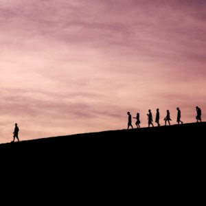 Silhouette of people on hill following each other